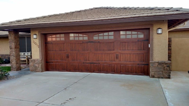 Dark cherry carriage house garage door with arched windows between stone columns