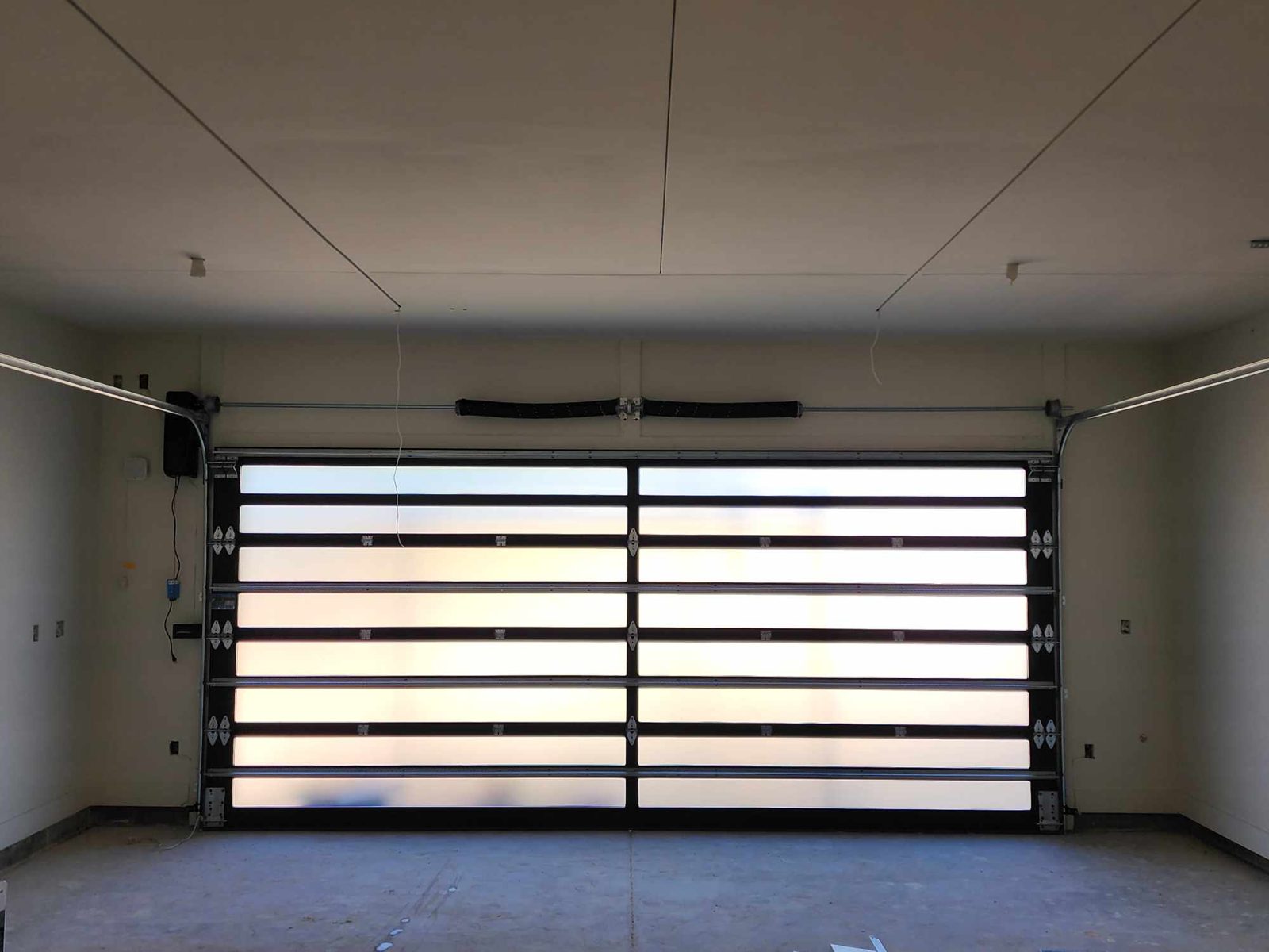 Frosted full view glass garage door glowing with daylight from inside the garage