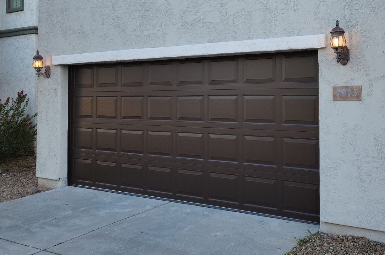 Coffee brown raised panel garage door, 16 by 7, on a stucco home