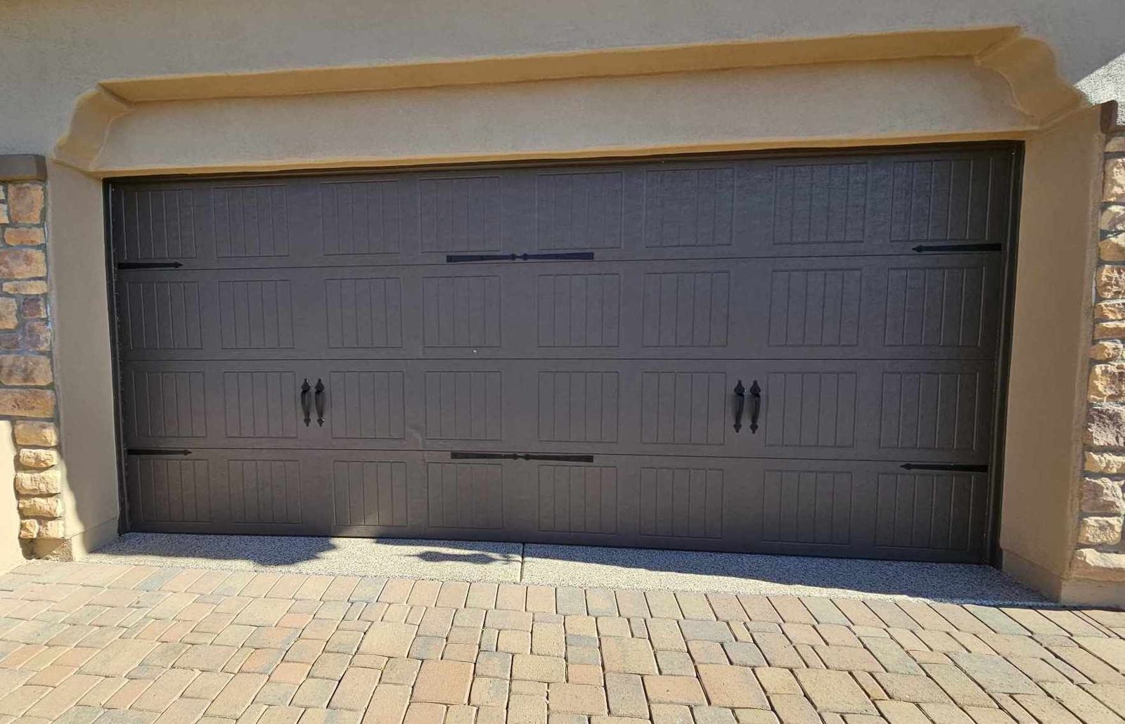 Dark bronze carriage style garage door with strap hardware in an arched opening