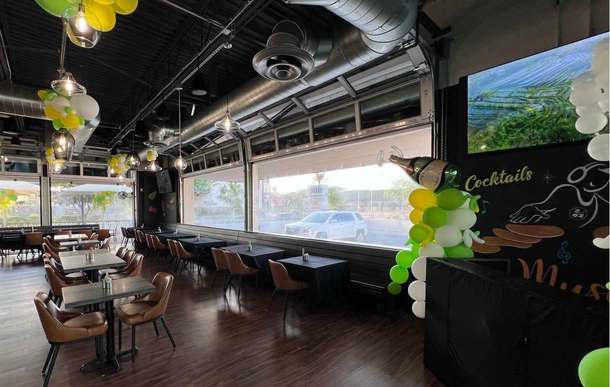 Full view glass garage doors opening a restaurant onto its patio