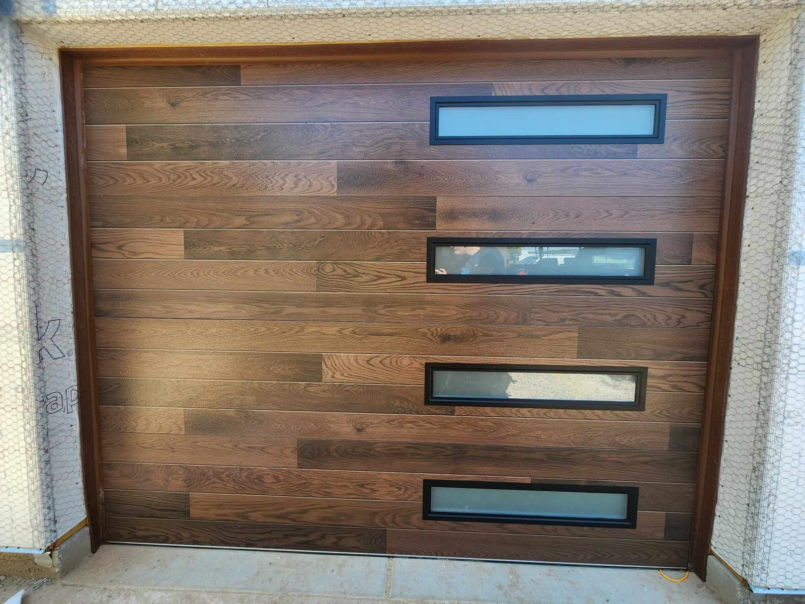 Dark wood grain modern garage door with four offset windows